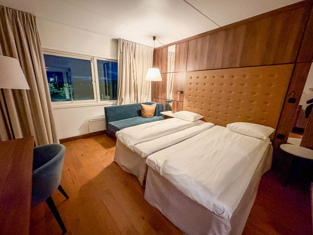 Cozy hotel room with two single beds, a window, and a sitting area.