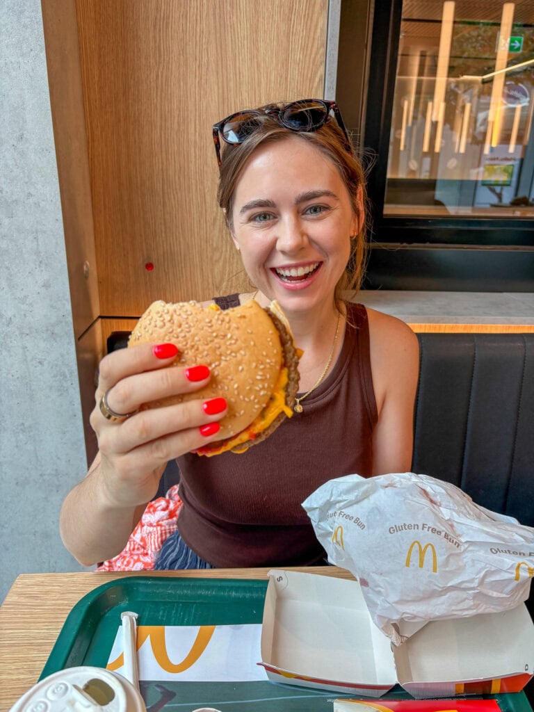 Happy woman enjoying a burger at a restaurant, promoting gluten-free dining in Oslo.