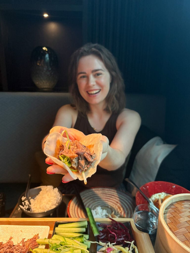 Happy woman holding a plate of gluten-free food at a restaurant in Oslo.
