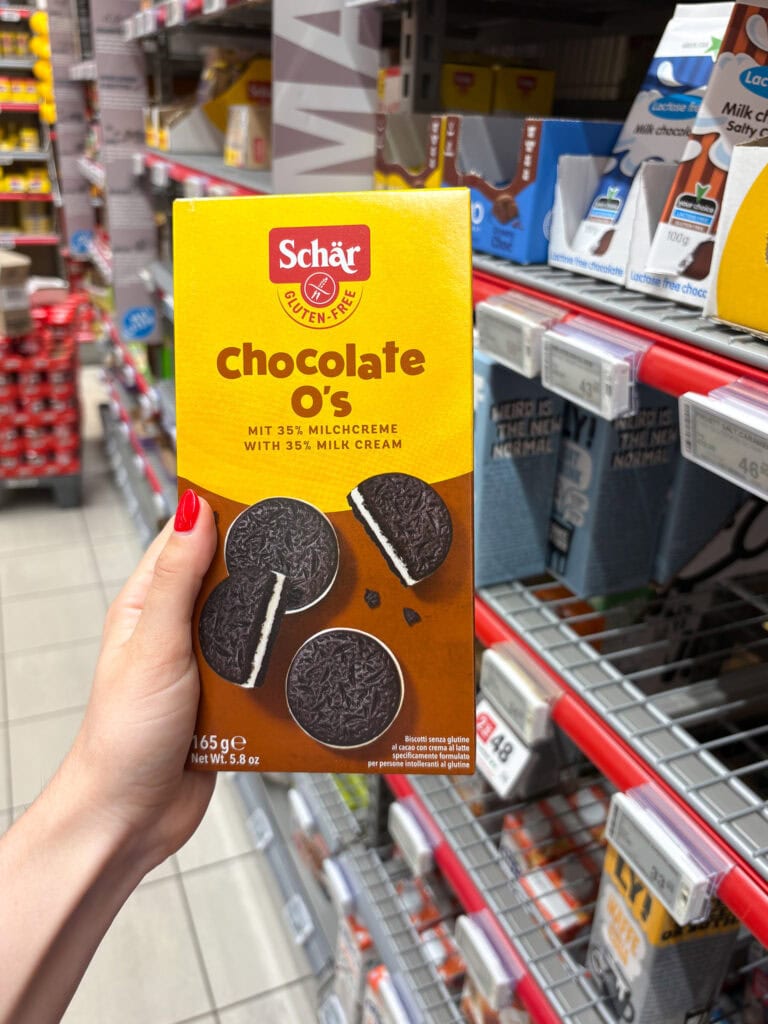 Vegan chocolate lollipops in a yellow Schär box on store shelf.