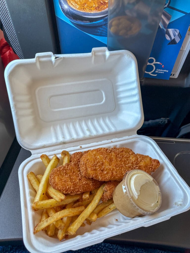Fried fish fillet with French fries and tartar sauce in a takeout box.
