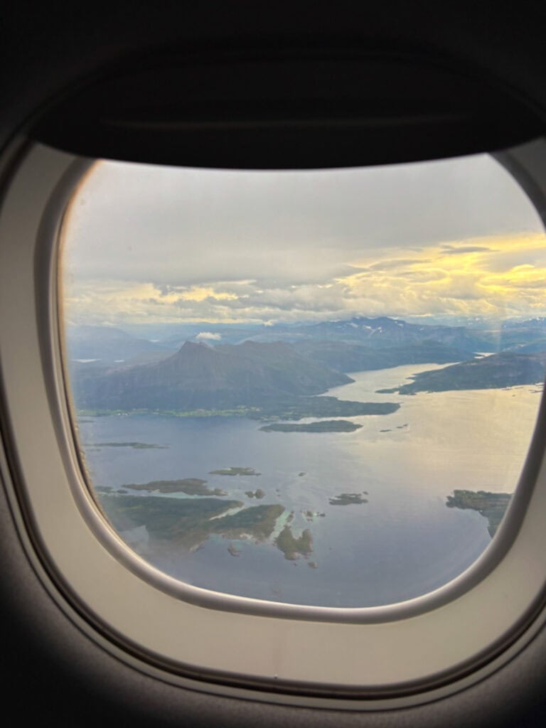 Aerial view of fjords and mountains seen from an airplane window in Norway.