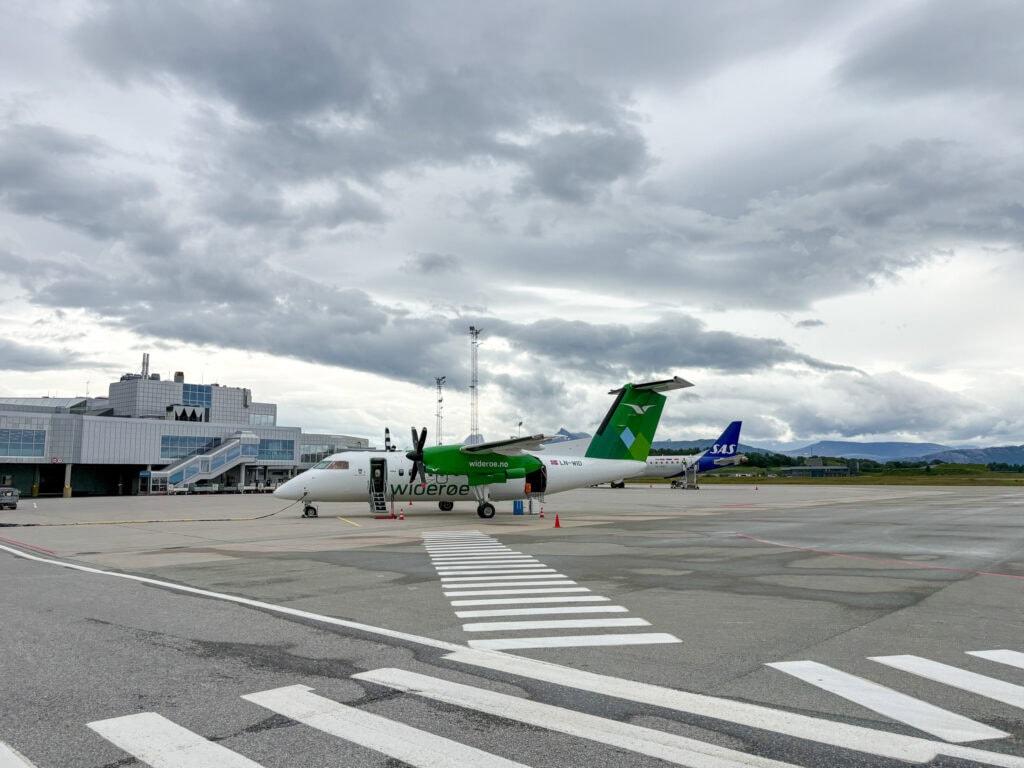 Small regional airport with parked aircraft under cloudy sky.