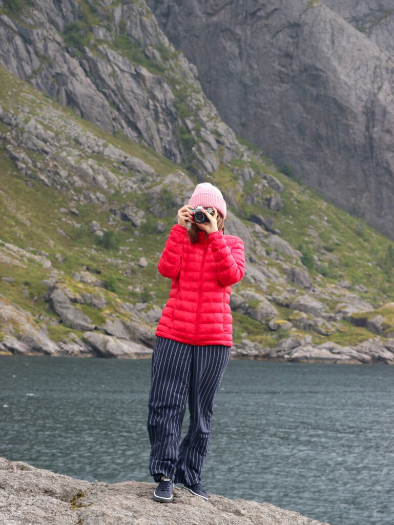 Person taking photos by a mountain lake in Lofoten, Norway.