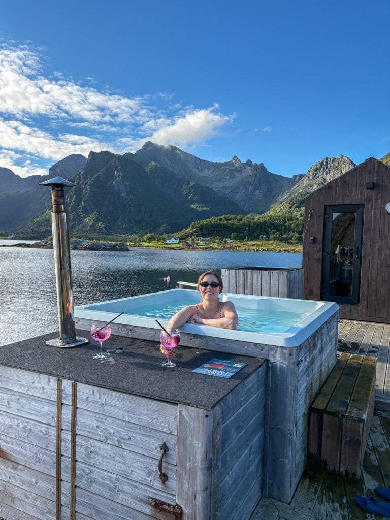 Woman relaxing in hot tub with mountain view in Lofoten, Norway.