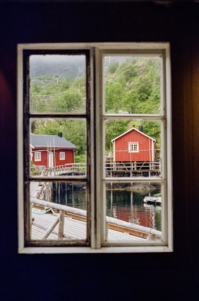 Scenic view of red houses by water seen through a window in Lofoten, Norway.