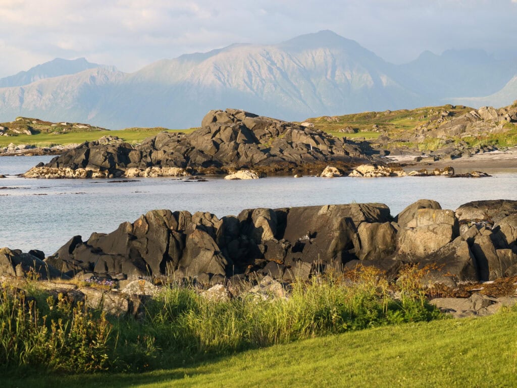 Scenic view of Lofoten Islands with rocky shoreline and mountains in the background.