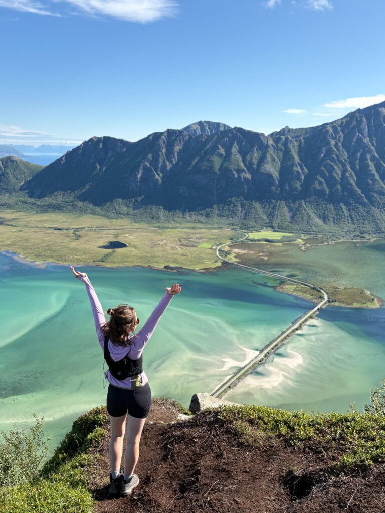 Woman overlooking a scenic mountain and lake landscape in Lofoten, Norway.