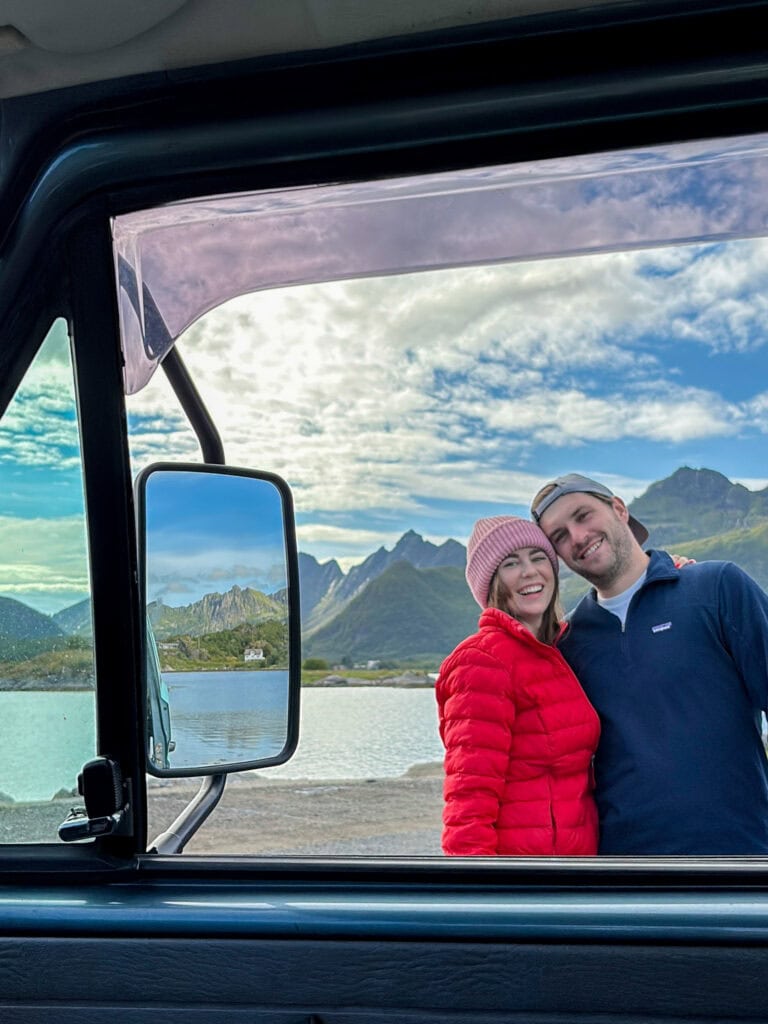 Couple enjoying Lofoten scenery from van with mountains and lake in background.