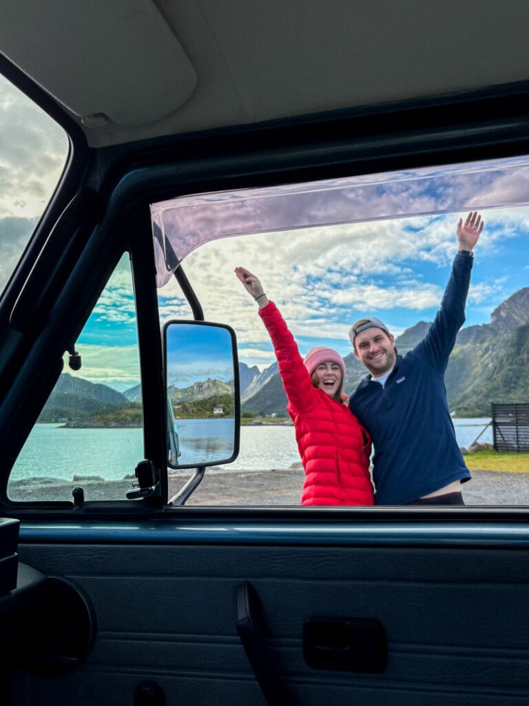 Happy couple enjoying Lofoten scenery from van window during van life adventure.