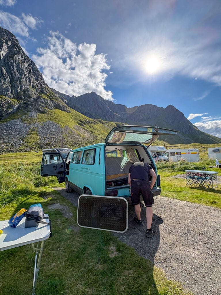 Van life in Lofoten with mountain views and outdoor setup under sunny sky.