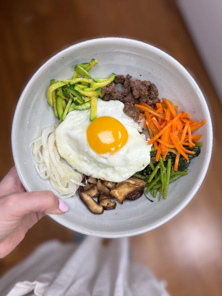 Korean bibimbap with vegetables, beef, egg, and mushrooms in a bowl.