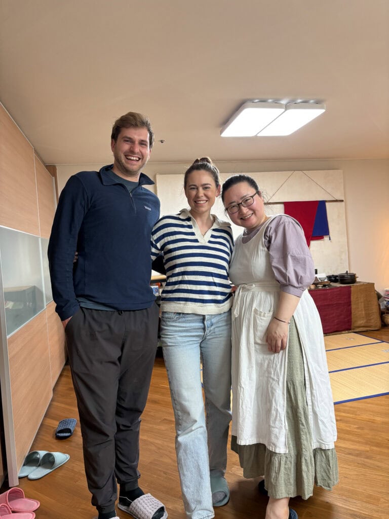 Group of three smiling people in a room, casual clothing, friendly atmosphere.