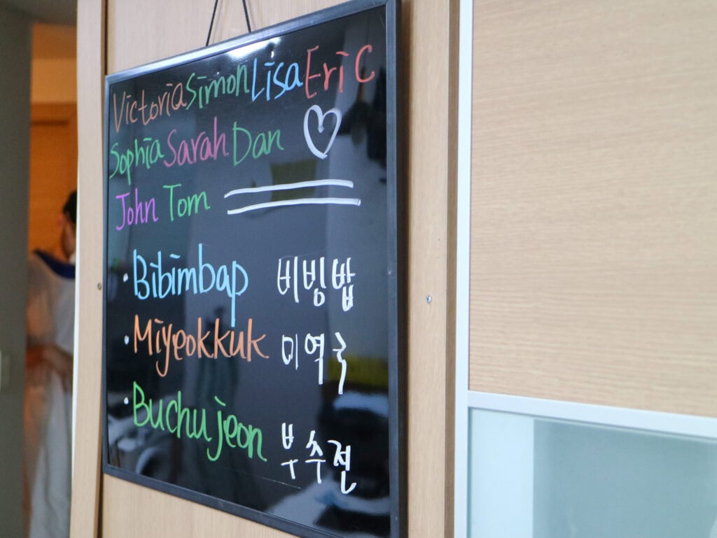 Colorful handwritten names on a blackboard at Busan cooking class.