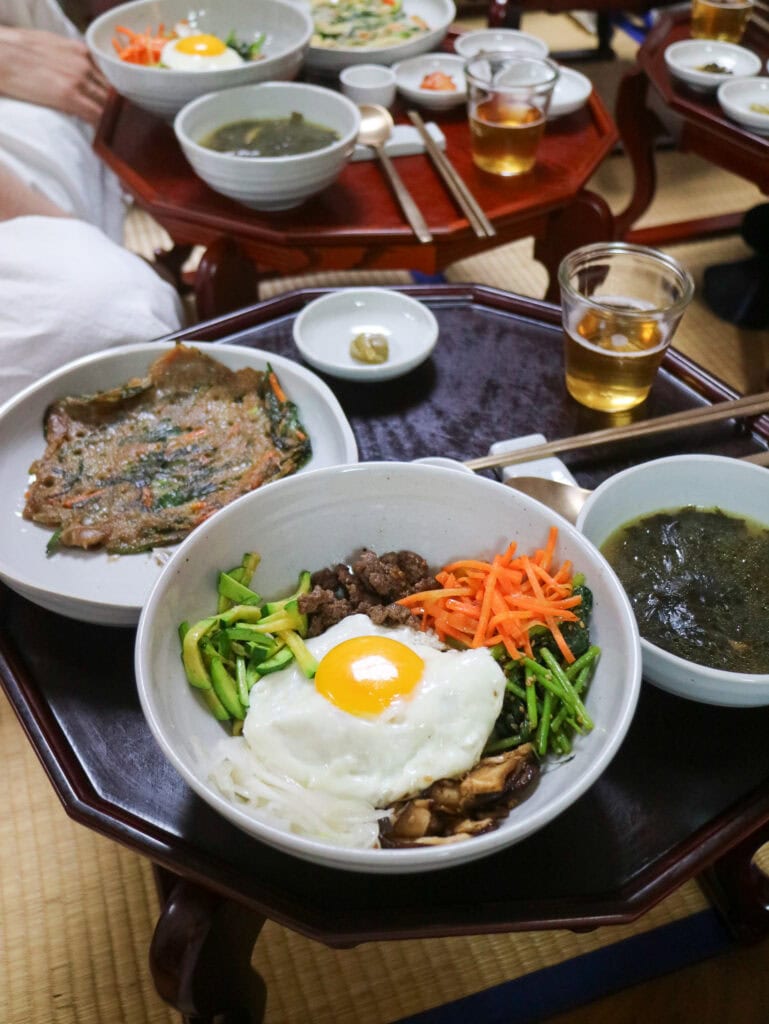 Authentic Korean meal with bibimbap, soup, and side dishes at a traditional restaurant.