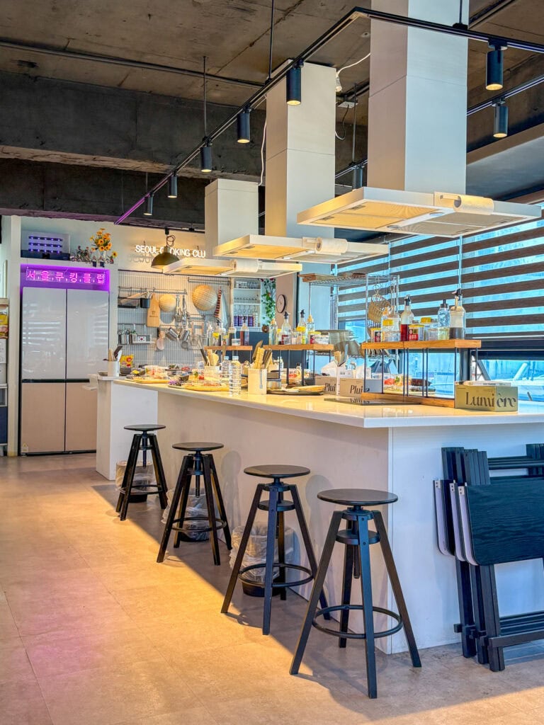 Modern Korean cooking class kitchen with bar stools and cooking equipment.