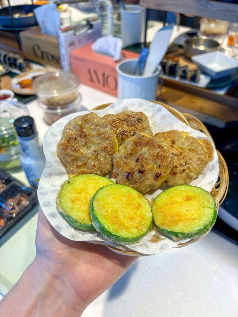 Korean fried patties and zucchini slices on a small basket plate.