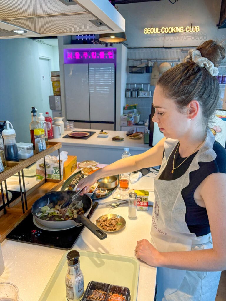 Woman cooking Korean dishes in a modern kitchen at Seoul Cooking Club.
