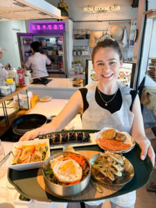 Happy woman holding a tray of Korean dishes at Seoul Cooking Club in Seoul.