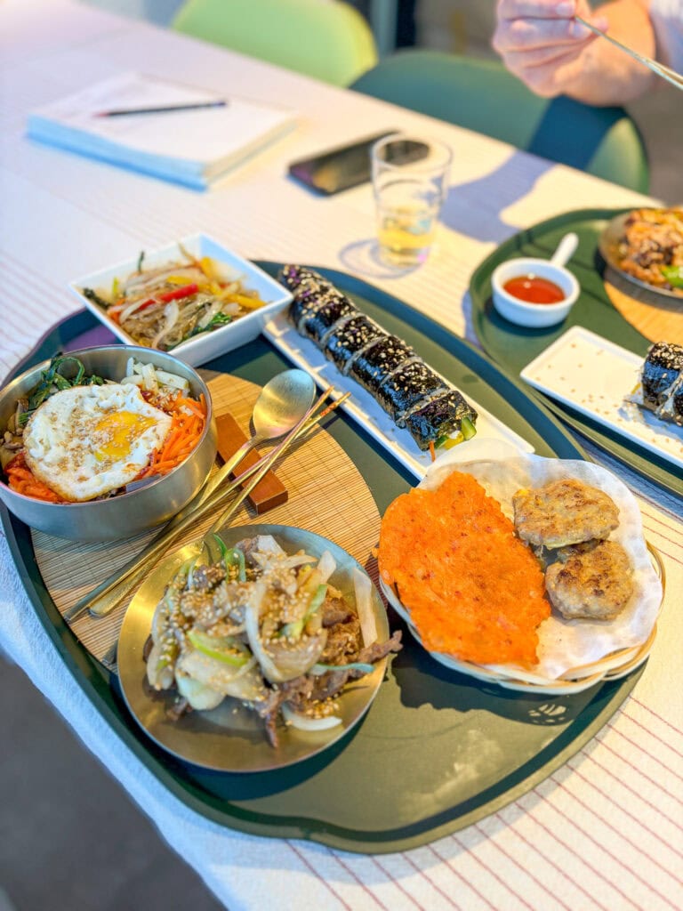 Assorted Korean dishes served on a table with chopsticks and sauces.