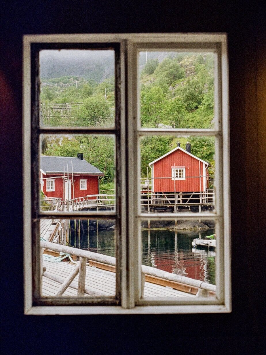Scenic view of red houses by water seen through a window in Lofoten, Norway.
