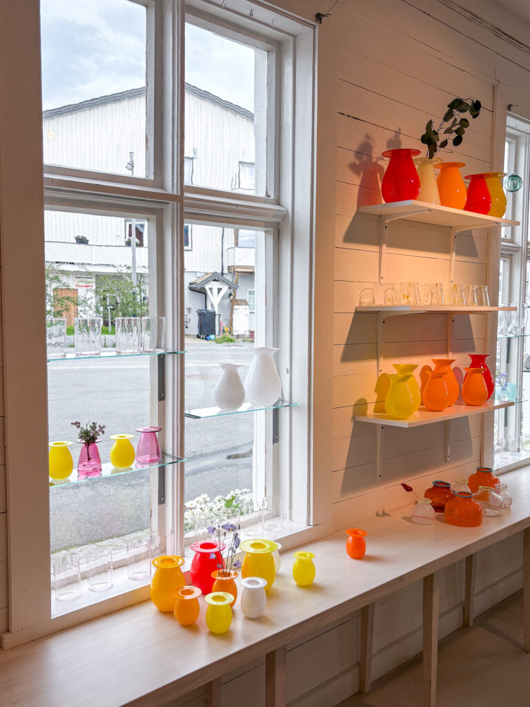 Colorful ceramic vases displayed on windowsill and shelves in a cozy shop.