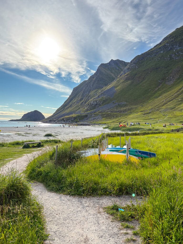 Scenic view of Lofoten with mountains, beach, and boats under a bright sky.