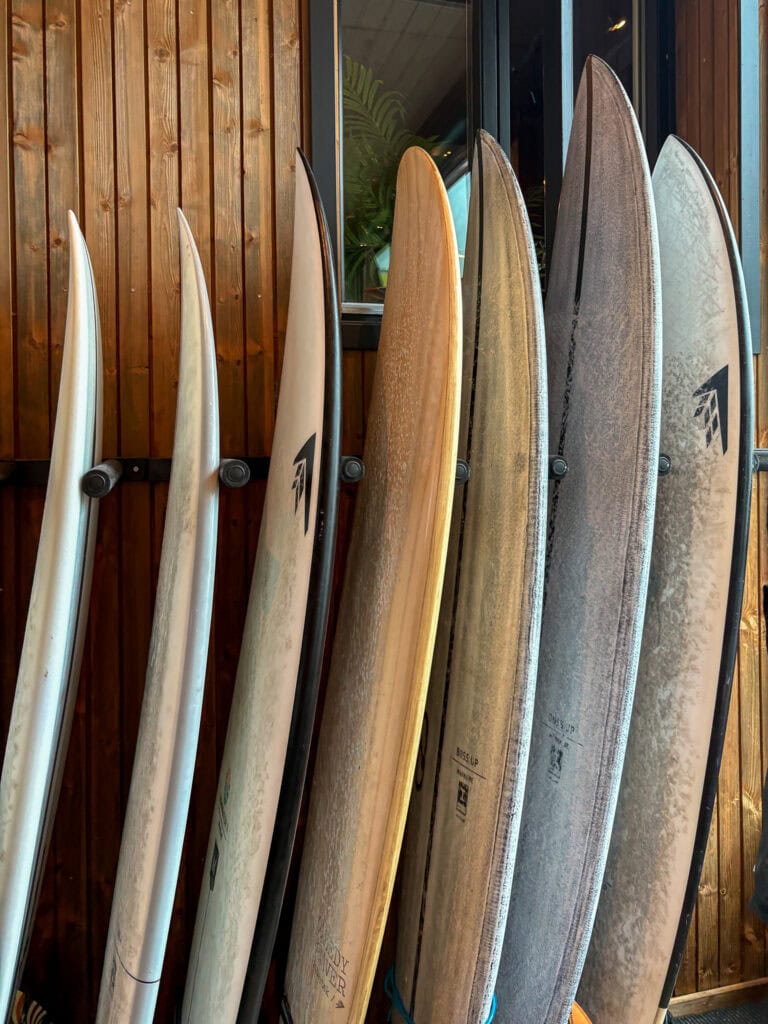 Collection of surfboards leaning against a wooden wall.